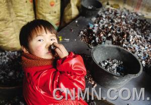 個小朋友在臺州市路橋區(qū)峰江街道一家拆解小作坊內(nèi)玩分揀出來的金屬。